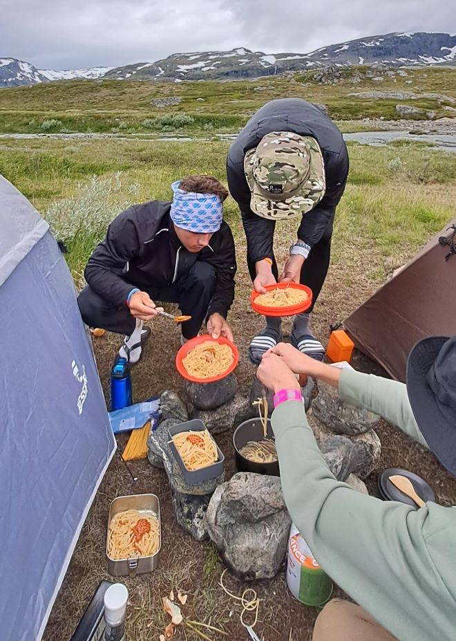 The four boys cooking pesto noodles between their tents, using the tents for shelter from the wind.