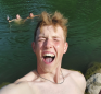 A portrait of a young man, Maxi, captured mid-scream of joy as he stands beside the Ybbs river.